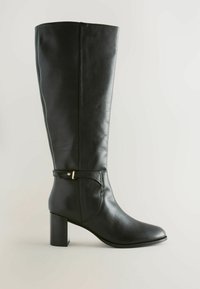 Bota de cuero negra hasta la rodilla con punta redondeada, tacón de bloque y una correa decorativa que presenta un pequeño acento dorado. Textura suave.