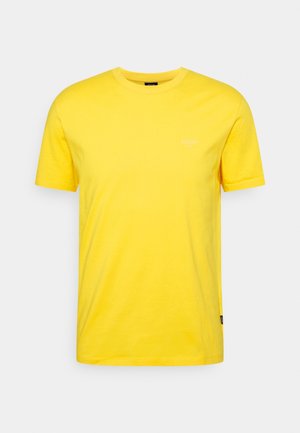 Gelbes T-Shirt mit kurzen Ärmeln und Rundhalsausschnitt, dezent mit weißem Logo auf der linken Brust und kleinem schwarzem Etikett an der linken Seitennaht.