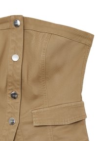 Beiger Korsett-Top mit strukturiertem Design, das mit silbernen Druckknöpfen, einer Tasche auf einer Seite und strukturiertem Stoff versehen ist.
