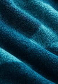 Strukturierter Fleece-Stoff in tiefem Teal, mit einer weichen, plüschigen Oberfläche, die Wellen und unterschiedliche Blautöne zeigt und Tiefe sowie Schichten demonstriert.