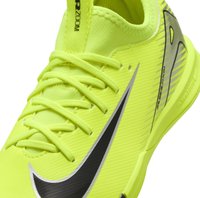 Zapatilla deportiva de color amarillo brillante con parte superior texturizada, logo negro y acentos reflectantes. Cuenta con cordones tradicionales y un diseño aerodinámico.
