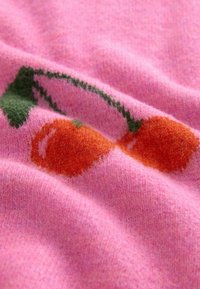 Pink knitted fabric featuring a pattern of two orange cherries and green leaves, showcasing a soft texture and smooth finish.
