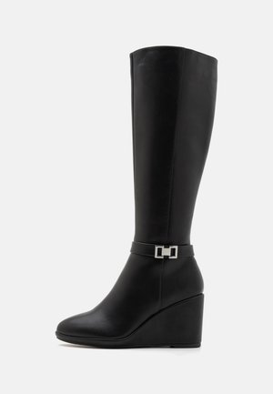 Bottes en cuir noir jusqu'aux genoux à talons compensés avec une finition lisse, présentant une boucle en argent décorative sur une sangle au-dessus de la cheville.