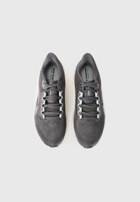Et par grå Nike løbesko med hvide såler og sorte snørebånd, set fra oven på en hvid baggrund.