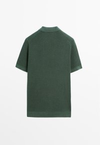 Polo a maniche corte in tessuto texturizzato verde scuro; presenta un colletto classico e polsini a costine. La vista posteriore mostra cuciture uniformi e orlo.