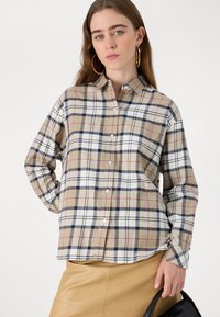 Beige plaid shirt with blue, red, and white accents. Button-up, long sleeves, and a relaxed fit. Smooth fabric with a slight sheen.