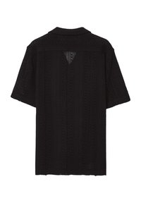 Chemise noire à manches courtes avec col polo, présentant un design texturé perforé et une légère ouverture en forme de V dans le dos.