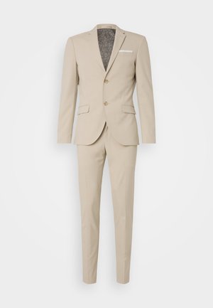 Traje beige con un diseño a medida, chaqueta de un solo botón y pantalones de frente plano. Forro interior con un patrón sutil.