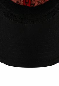 Chapeau seau noir avec une doublure intérieure texturée et à motifs dans des tons d'orange et de rouge, présentant des détails de couture subtils sur le bord.