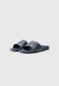 Mørkeblå gummislip-on sandaler med en bred strukturert stropp som har hevet logo og et mønstrete fotseng for grep. Flat såle for komfort.