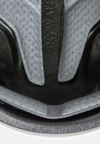 Svart och grå hjälminredning med texturerad stoppning, med perforerad yta för ventilation och upphöjt logotypdetalj.