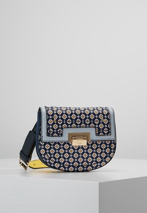 Lille crossbody taske med navy, hvid og sennepsfarvet geometrisk mønster, lyseblå kant og guldtonet rektangulær spænde på frontklappen.