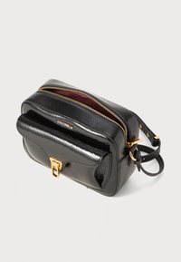 Black leather handbag with a glossy finish, two zippered compartments, a front flap, and gold-tone hardware accents. Textured surface detail.