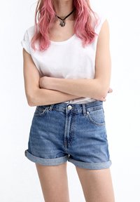 Vaaleansinisen pesun farkkushortsit, joissa ovat käännetyt reunat ja kaksi etutaskua. Yhdistetty valkoiseen lyhythihaiseen t-paitaan. Musta kaulapanta-asuste.