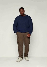 Μπλε ναυτικό πλεκτό πουλόβερ, παντελόνια cargo και λευκά αθλητικά παπούτσια. Το πουλόβερ είναι χοντρό και με υφή, ενώ τα παντελόνια έχουν τσέπες και άνετη εφαρμογή.