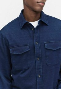 Marineblauwe denim overhemd met twee borstzakken, knoopkraag en een gestructureerde afwerking. Kenmerkt zich door donkere knopen en een klassiek ontwerp.