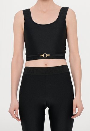 T-shirt cropped noir avec larges bretelles, présentant un accent circulaire doré et une ceinture texturée avec l'inscription "JUST CAVALLI".
