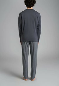Set di abbigliamento da casa per uomo composto da una maglia a maniche lunghe grigia scura e pantaloni a righe grigi chiari, entrambi realizzati in un tessuto morbido e traspirante.