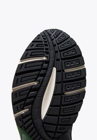 Semelle de chaussure en caoutchouc noir avec des motifs de crantage texturés, accents gris clair et une semelle intermédiaire lisse pour une meilleure adhérence et un soutien accru.
