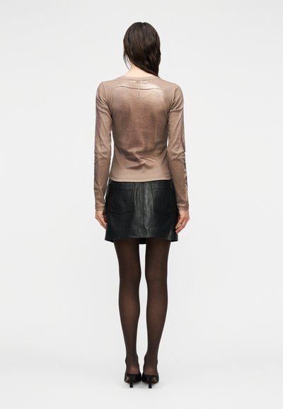 Καφέ μακρυμάνικη μπλούζα με εφαρμοστή σχεδίαση, διαθέτει ελαφριά γυαλάδα και στρογγυλή πλάτη. Συνδυάζεται με μαύρη μίνι φούστα από δέρμα.