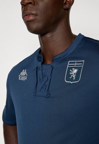 Marineblaue Kappa-Shirt aus strukturiertem Stoff, mit Henley-Ausschnitt und gesticktem Wappen mit einem Löwen. Enthält Logo auf der linken Seite.