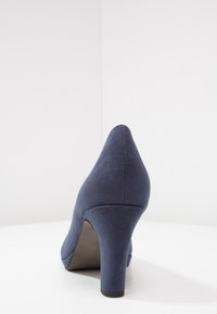 Scarpa con tacco alto blu navy in materiale scamosciato, con punta appuntita e tacco spesso. Texture liscia con minimi dettagli.