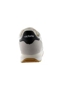 Zapatilla blanca y gris con parte superior de ante y tela, acento negro en el talón y media suela blanca. Presenta el logo "victoria" en el talón.
