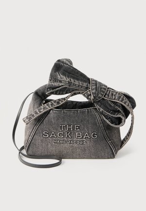 Μαύρη τσάντα από τζιν με μεγάλο δεμένο φιόγκο και ιμάντα ώμου, κεντημένη με το κείμενο "THE SACK BAG MARC JACOBS" στο μπροστινό μέρος.