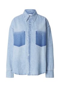 Camicia in denim azzurro chiaro con due tasche a toppa in blu più scuro, chiusura frontale con bottoni, maniche lunghe e colletto classico. Tessuto morbido.
