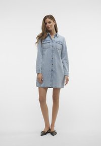 Gaiši zils džinsa kleita ar garām piedurknēm, priekšējiem pogām un divām krūšu kabatām. Raksturīga taisna silueta un apkakles izgriezums.