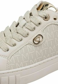 White sneaker featuring a textured leather upper with perforated pattern, metallic accents, and light gray laces. Flat rubber sole.