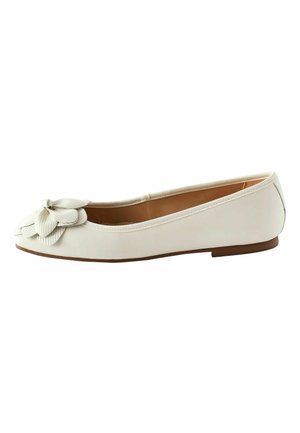 Chaussure de ballet plate blanche avec un bout rond et un détail floral superposé décoratif à l'avant, et une semelle basse marron.