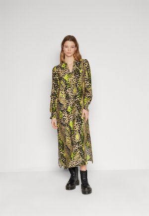 Long-sleeve, animal print dress in beige, black, and green. Features a collared neckline and flowing silhouette, paired with black combat boots.