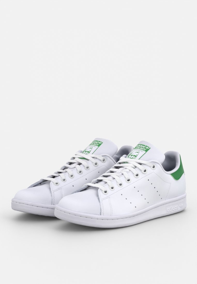 Baskets en cuir blanc avec des accents verts sur le talon, des détails perforés sur les côtés et des semelles en caoutchouc blanches. Elles présentent des lacets plats et des étiquettes de logo.