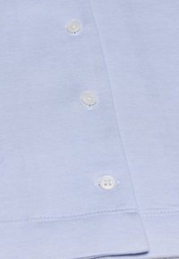 Lichtblauw gebreid shirt met drie witte knopen; gladde textuur; eenvoudig ontwerp; klassieke kraag; nette afwerking aan de zoom.