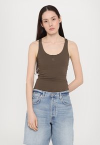Top in cotone marrone con scollatura a barca e design aderente, abbinato a pantaloni corti in denim blu chiaro. Presenta un logo discreto vicino al petto.