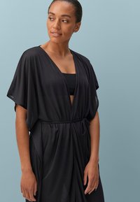 Zwarte lichtgewicht kimono-stijl robe met korte mouwen, een V-hals en een strikceintuur in de taille. Semi-doorzichtig materiaal en een relaxte pasvorm.