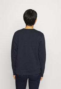 Sudadera azul marina con cuello redondo, mangas largas y puños y dobladillo acanalados. Tejido suave, diseño sencillo y sin patrones visibles.