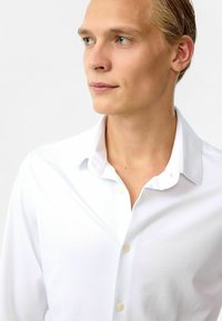 Witte blouse met een gespreide kraag en lichtbruine knopen, met een gladde textuur en een getailleerde pasvorm voor een nette uitstraling.