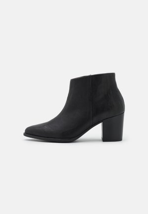 Bottine noire en cuir avec un bout arrondi et un talon bloc épais, présentée sur un fond blanc uni.
