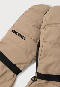 Beige Burton-merk wanten met zwarte verstelbare polsbanden en een kleine zwarte plastic clip op een van de wanten.