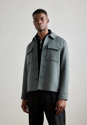 Gray wool blend jacket with a collared neckline, front buttons, and two chest pockets. Smooth texture and tailored fit.