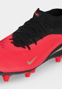 Φωτεινό κόκκινο και μαύρο παπούτσι Nike με ψηλό κολάρο αστραγάλου, μαύρα κορδόνια, υφασμένη επάνω επιφάνεια και αγκράφες στην σόλα για αθλητική χρήση.
