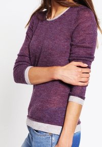 Fioletowy sweter z długim rękawem wykonany z miękkiej dzianiny, z jasnoszarym prążkowanym dekoltem i dołem. Dopasowany fason o subtelnej fakturze.