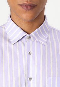 Light purple striped shirt with a pointed collar, front pocket, and two-button fastening. Fabric appears smooth with a soft texture.