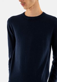Maglione blu navy scuro realizzato in un tessuto morbido, con scollatura rotonda e maniche lunghe. La trama appare liscia con una leggera peluria.