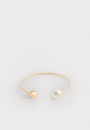 Bransoletka na nadgarstek w złotym kolorze, z złotą i białą perłą na każdym końcu, o gładkim, minimalistycznym designie i okrągłym, otwartym kształcie.