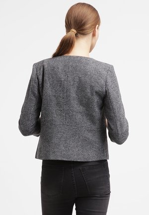 Blazer texturé gris avec une coupe ajustée, un design légèrement court et des manches longues. Le dos présente des coutures et une silhouette minimaliste.