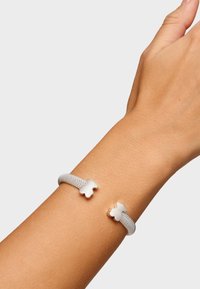 Pulsera de malla plateada que presenta dos acentos en forma de oso en metal pulido. Textura suave con un ajuste flexible en la muñeca.
