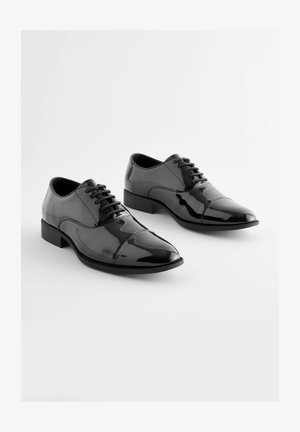 Schwarze Lackleder-Dress-Schuhe mit spitz zulaufender Zehe, Schnürdesign und niedrigem Absatz. Glatte Oberfläche mit leichtem Glanz.